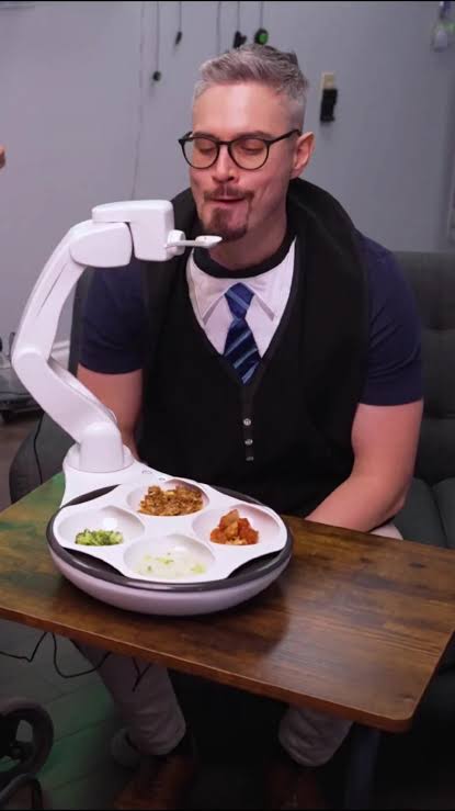 Person using the Obi robotic feeder during a meal